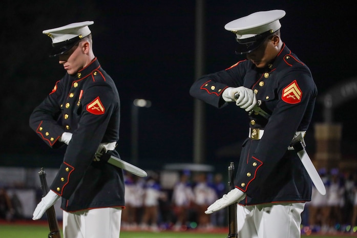 U.S. Marine Corps Lance Cpl. Kyle Uhlar and Cpl. Jacob Dobromirescu, riflemen with the United States Marine Corps Silent Drill Platoon, execute the "double inspection" sequence during a half-time performance at a Gainesville High School football game during Marine Week Atlanta in Gainesville, Ga., Aug. 29, 2025. The year 2025 marks the 250th anniversary of the United States Marine Corps, a milestone that highlights the legacy, transformation and enduring spirit of the Corps since 1775. Throughout the year, Marines across the globe will commemorate this anniversary by honoring the service and sacrifice of those who served before them and by remaining faithful to the motto Semper Fidelis. (U.S. Marine Corps photo by Cpl. Christopher Prelle)