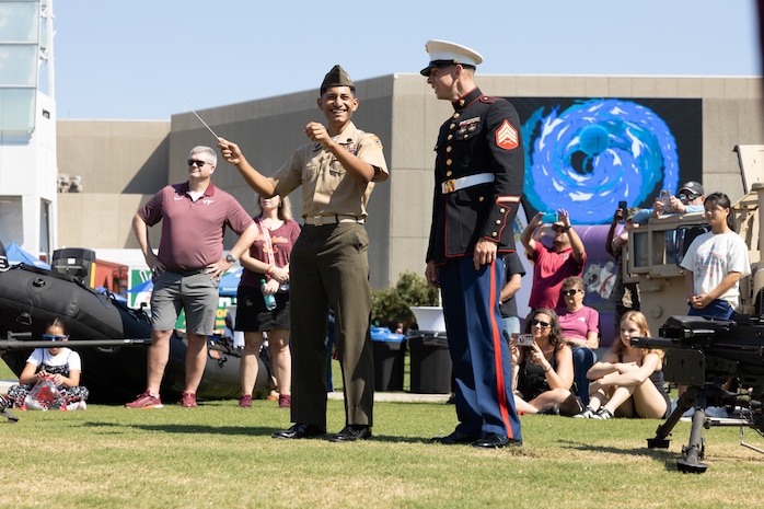 U.S. Marine Corps Sgt. Taylor Brown, (Right), a musician with the 2nd Marine Aircraft Wing Band, assigned to Special Purpose Marine Air-Ground Task Force-250, allows a member of the Young Marines Program to experience conducting the band during Marine Week Atlanta, Aug. 31, 2025. Marines stationed across the globe commemorate the 250th anniversary of the Marine Corps, honoring a distinguished legacy of service, sacrifice, and unwavering fidelity to both the nation and fellow Marines. (U.S. Marine Corps photo by Lance Cpl. Kiara Rawls)