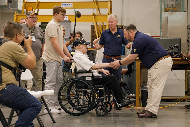 U.S. Marine Corps veteran Cpl. Leighton Willhite, who served in the Battle of Iwo Jima, left, shakes hands with Jonathan Bernstein, curator of arms and armor at the National Museum of the Marine Corps, right, at the Museum Support Facility in Dumfries, Virginia.