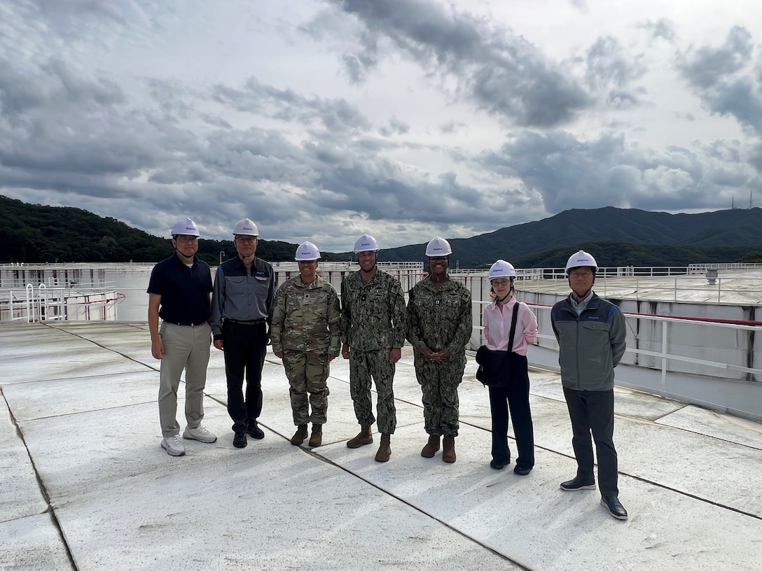 RDML Bresnihan (center) stands atop a fuel storage tank at DFSP Pyeongtaek with Army Lt. Col Van (center left), Navy Lt. Cleopatra Haynes (center right) and representatives from a Korean energy supplier partner.