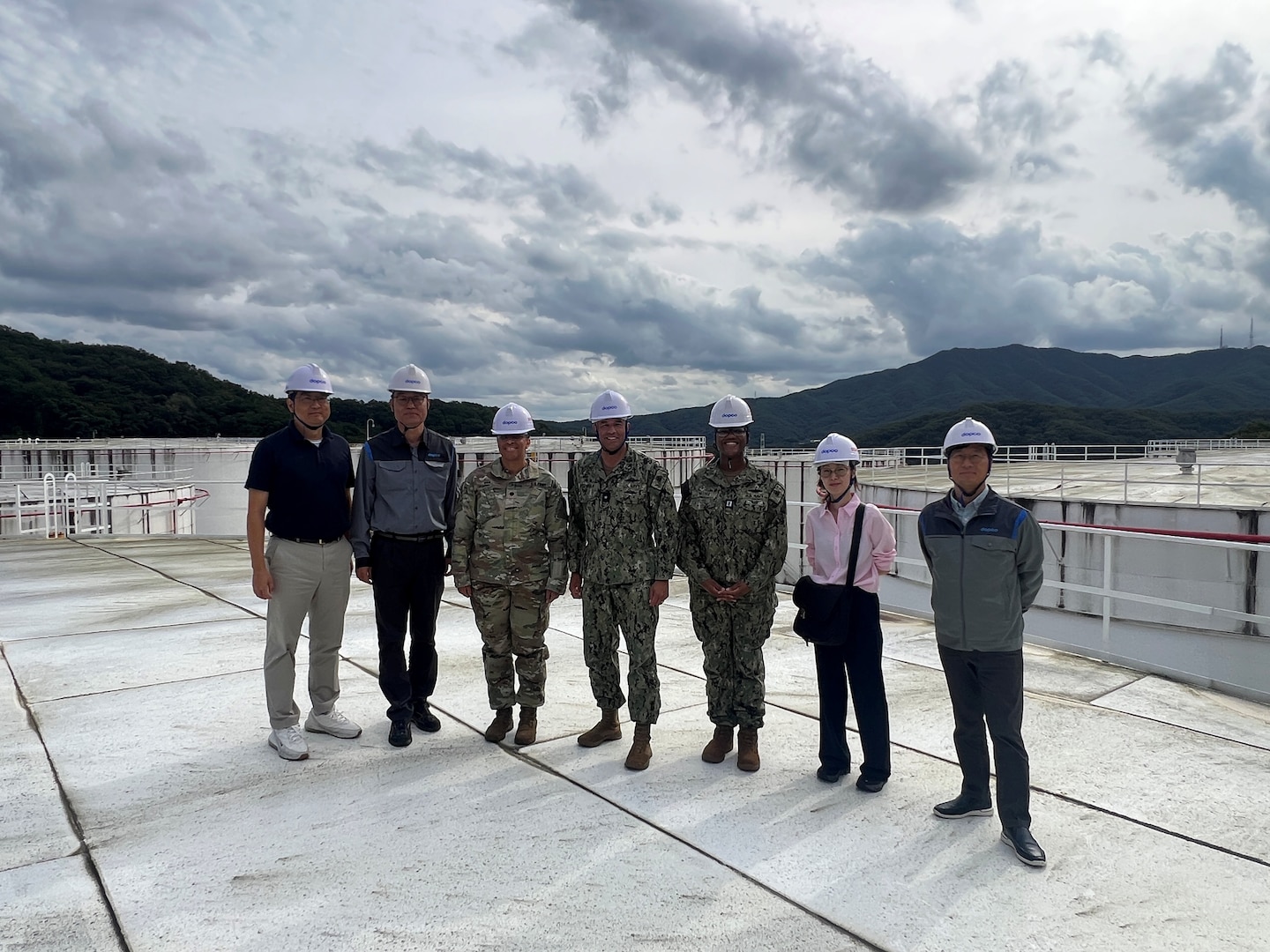 RDML Bresnihan (center) stands atop a fuel storage tank at DFSP Pyeongtaek with Army Lt. Col Van (center left), Navy Lt. Cleopatra Haynes (center right) and representatives from a Korean energy supplier partner.
