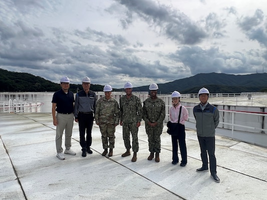 RDML Bresnihan (center) stands atop a fuel storage tank at DFSP Pyeongtaek with Army Lt. Col Van (center left), Navy Lt. Cleopatra Haynes (center right) and representatives from a Korean energy supplier partner.
