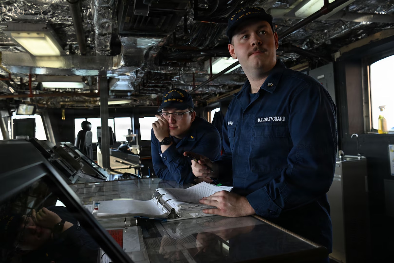 Two service members stand at a counter inside a military ship.