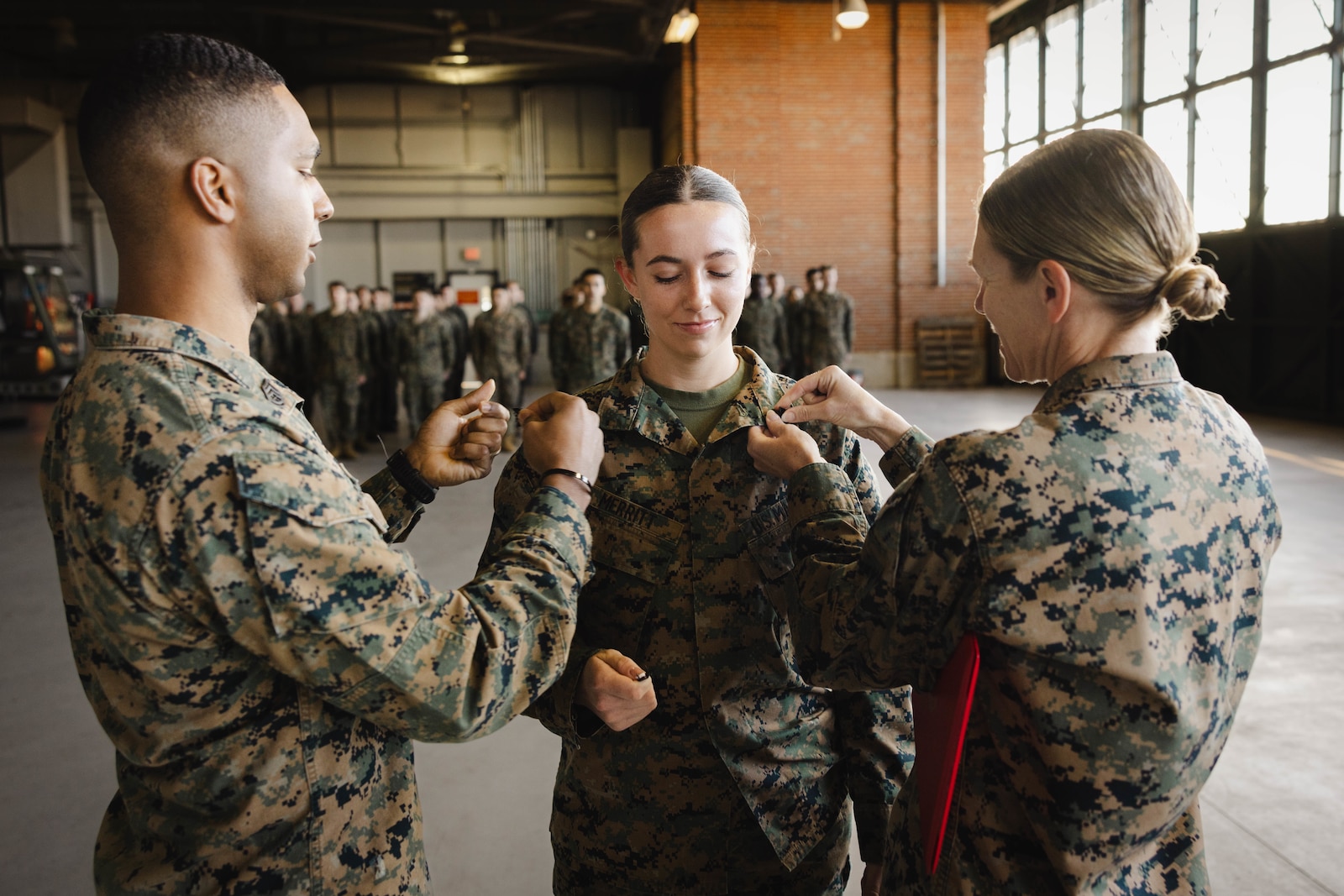 U.S. Marine Corps Gunnery Sgt. Kenny Jules, an expeditionary firefighting and rescue training chief with Marine Corps Air Facility, left, and Col. Jenny Colegate, base commander of Marine Corps Base Quantico, right, pins Sgt. Kayli Merritt, an expeditionary firefighting and rescue specialist with MCAF, during her meritorious promotion to sergeant at MCAF on MCB Quantico, Virginia, Nov. 24, 2025. A meritorious promotion is based on the individual Marines ability to take on the responsibilities and duties of a higher grade in an effective manner. (U.S. Marine Corps photo by Lance Cpl. Harleigh Faulk)