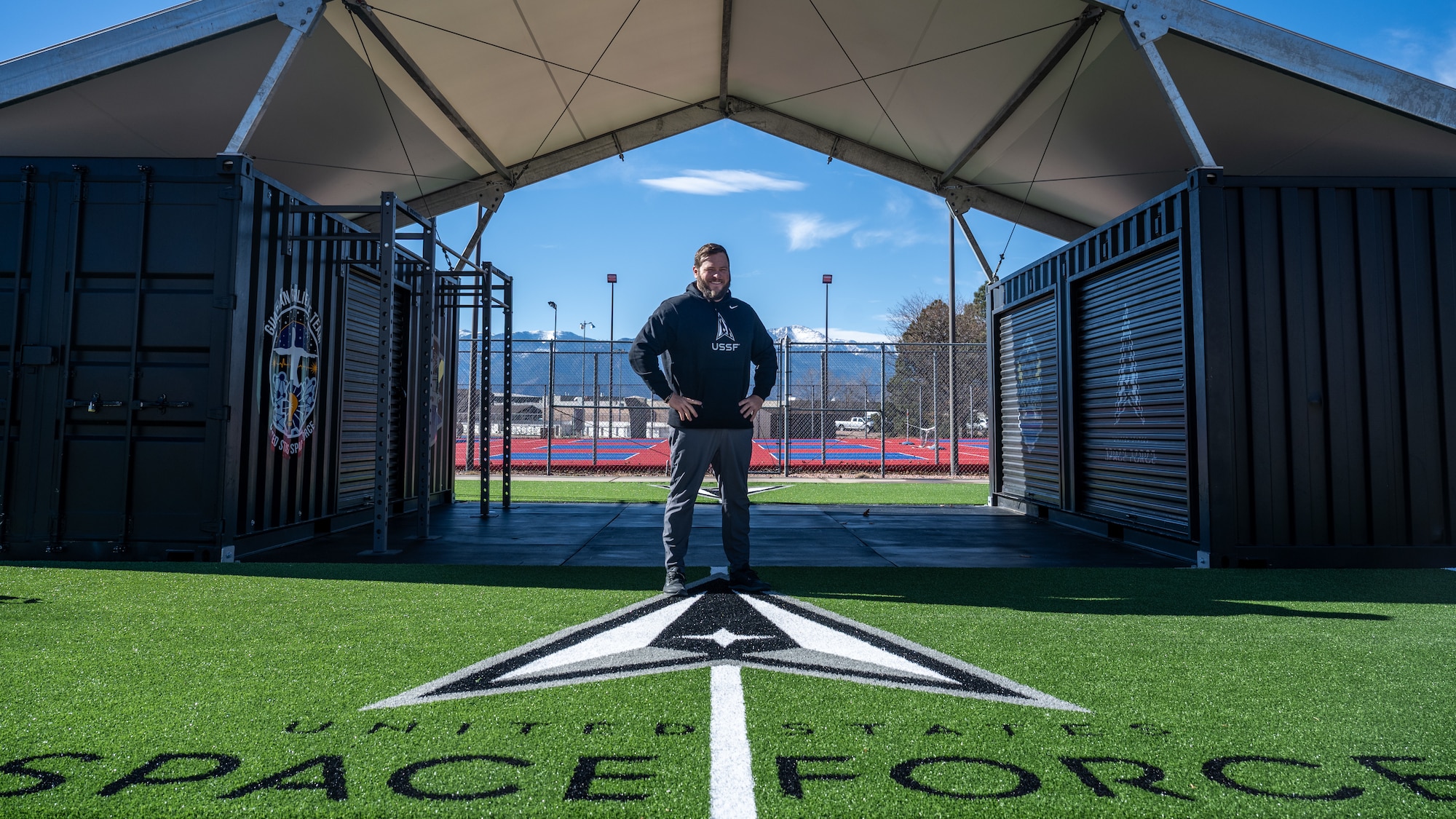 Man stands in front of workout equipment outside.