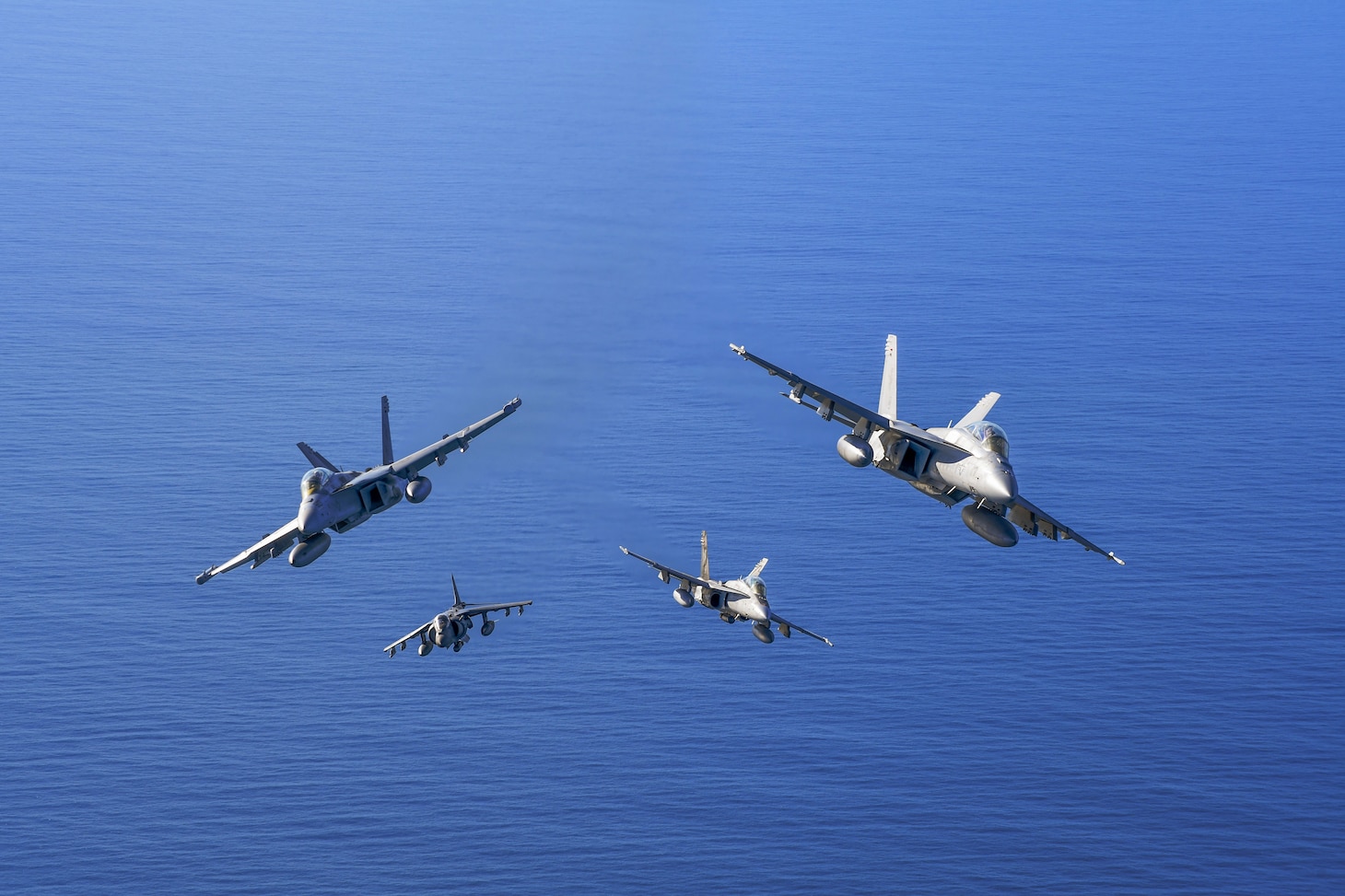 A formation of VX-31 ‘Dust Devils’ aircraft, including an EA-18G Growler, AV-8B+ Harrier, and two F/A-18E Super Hornets, flies over Point Mugu's Sea Range during a photo exercise. These aircraft demonstrate the Naval Air Warfare Center Weapons Division's commitment to advancing fleet capabilities through rigorous testing and operational support.