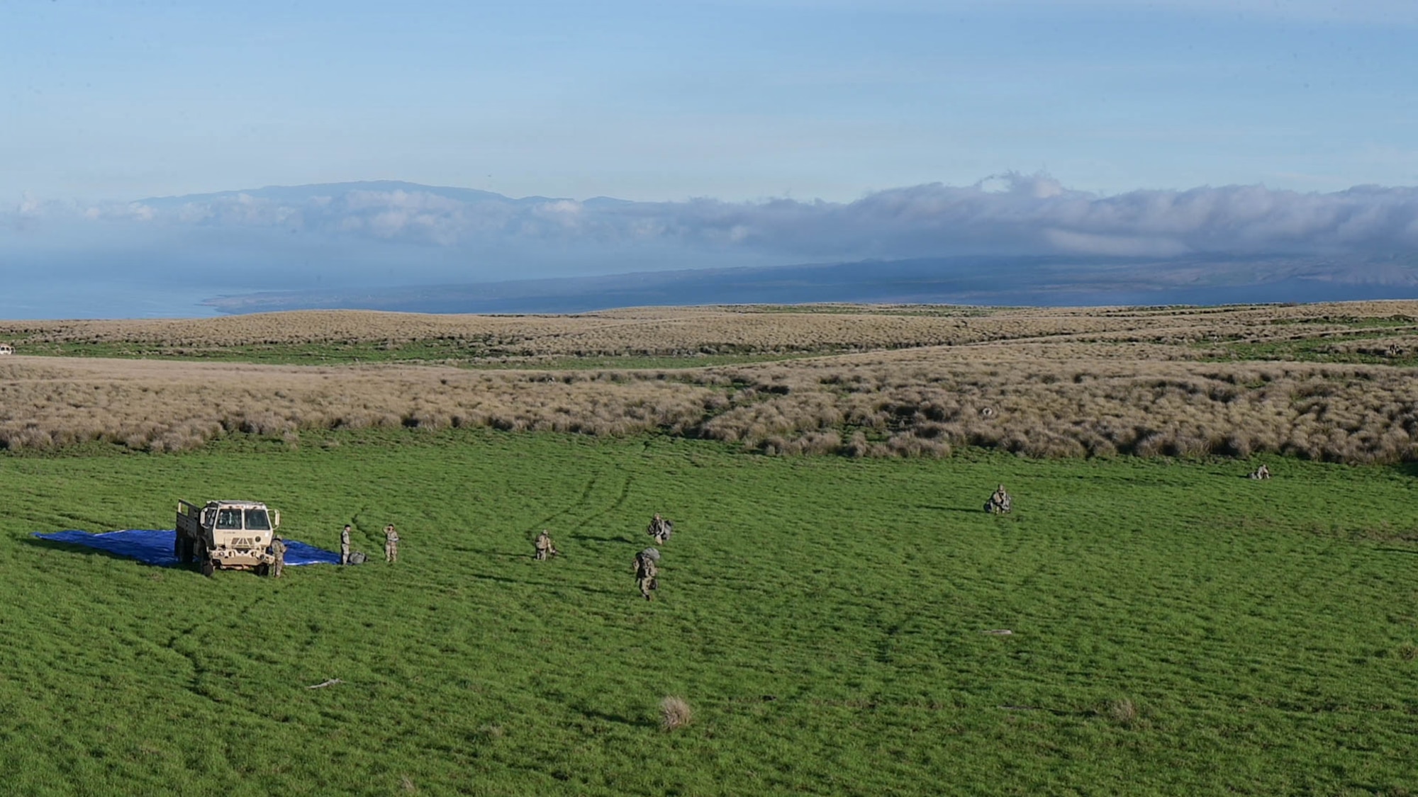 Soldiers walk towards a U.S. Army vehicle in a field.