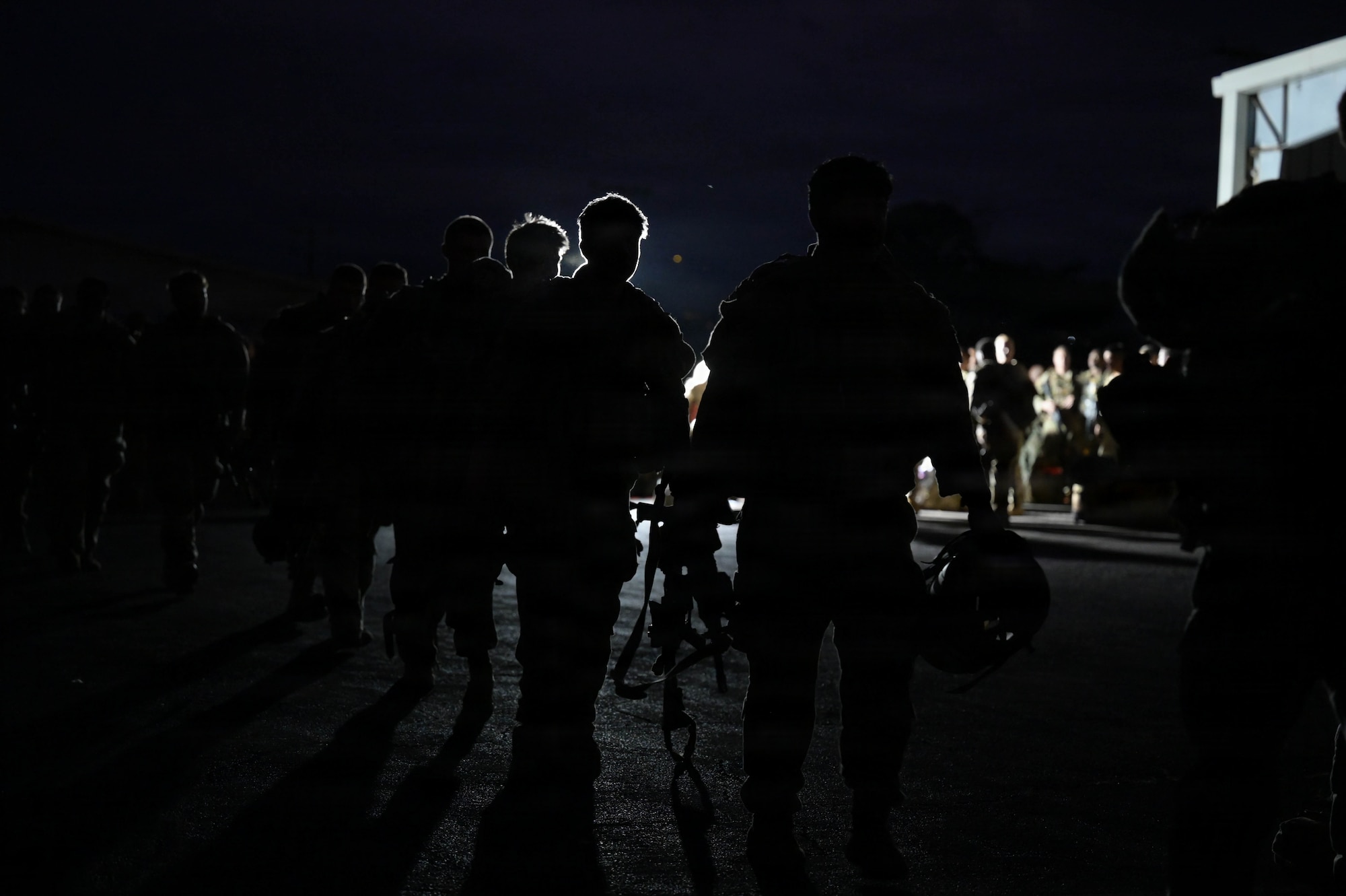 U.S. Army soldiers walking on a flightline at night.