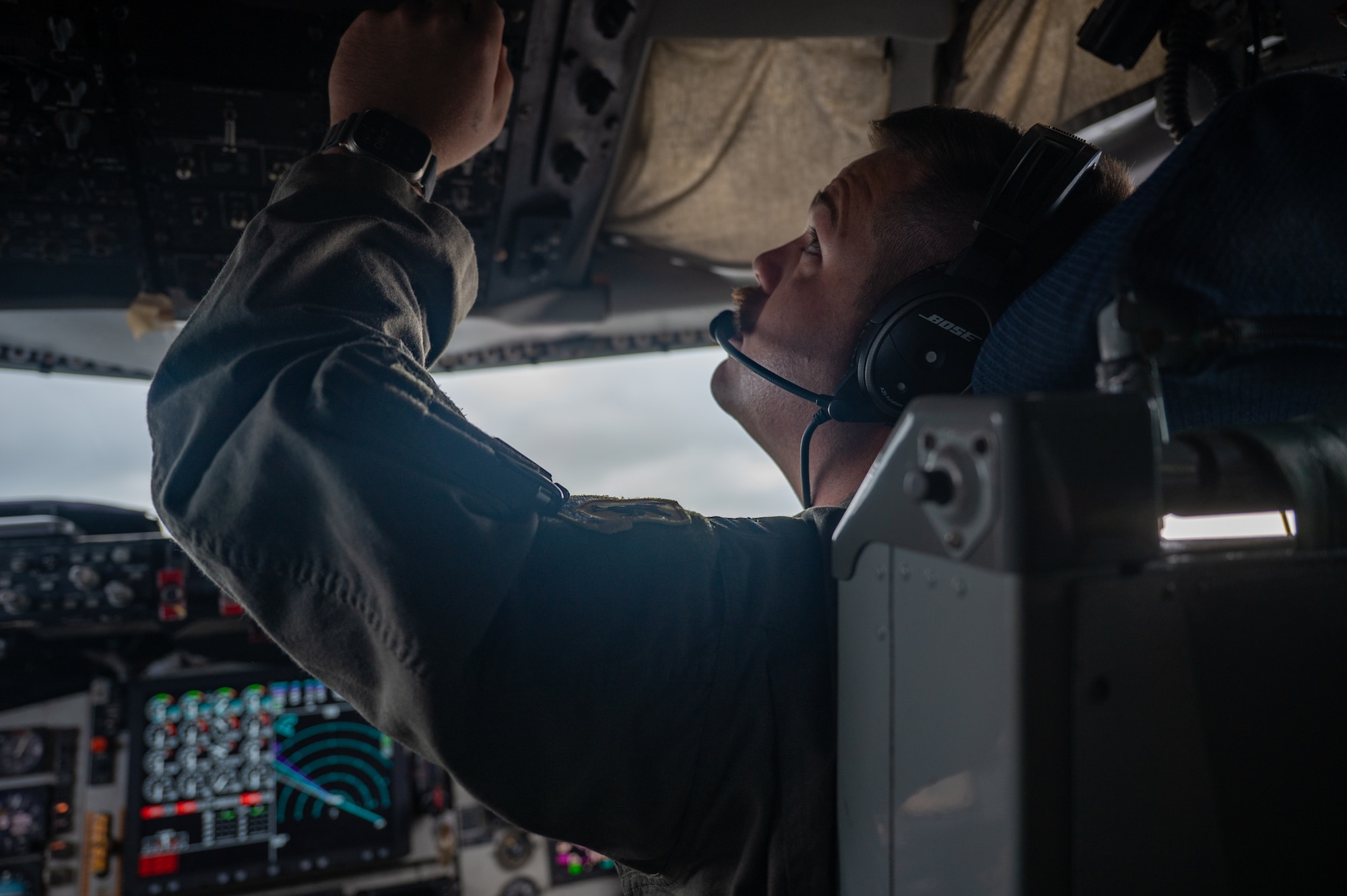 A man flicks an overhead switch on the flightdeck of a KC-135 Stratotanker.