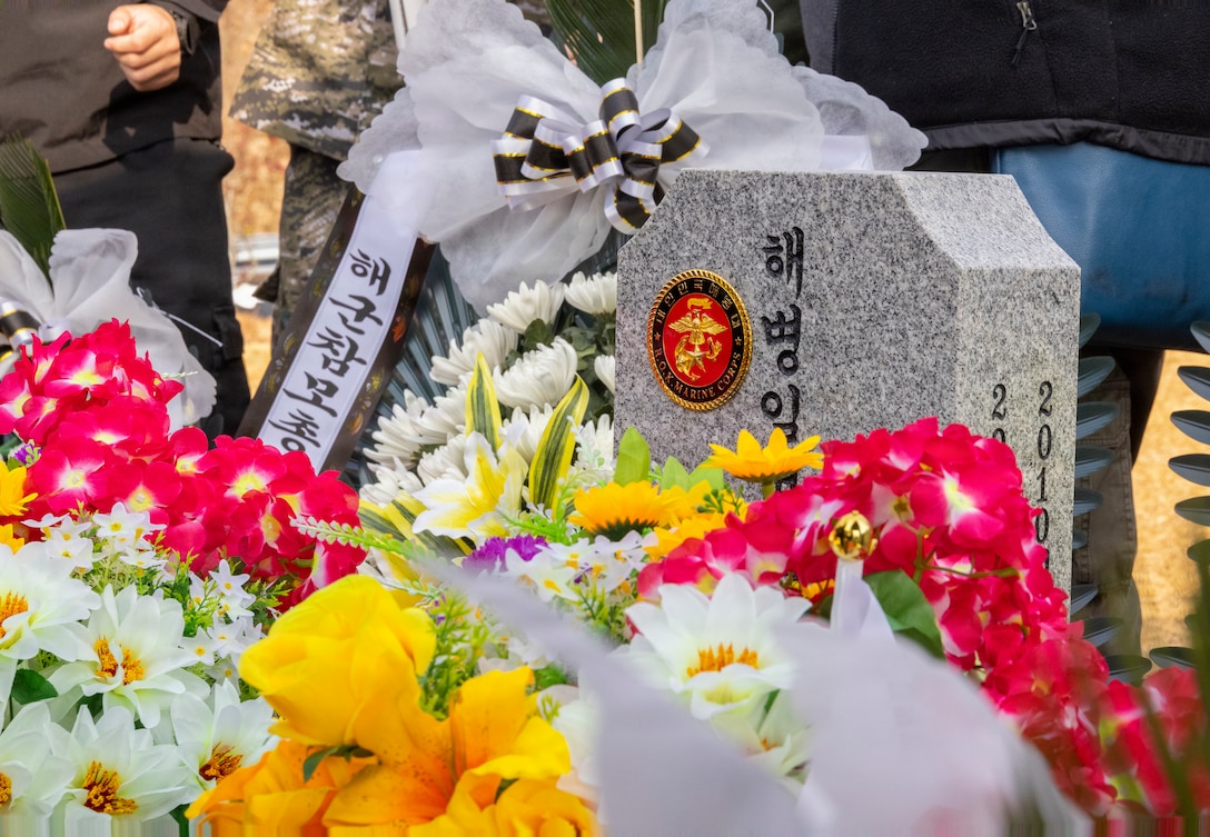 Flowers are placed at the headstone of a fallen Republic of Korea Marine during a memorial ceremony for the 15th anniversary of the Bombardment of Yeonpyeong to honor the fallen ROK Marines and their unwavering actions in defense of their country, on Nov. 23, 2025. On Nov. 23, 2010, upon receiving North Korean artillery fire on Yeonpyeong Island, ROK Marine Corps forces responded swiftly and decisively with artillery counterfire to successfully defend the island in what is known today as the Bombardment of Yeonpyeong. (U.S. Marine Corps photos by Cpl. Simon Saravia)