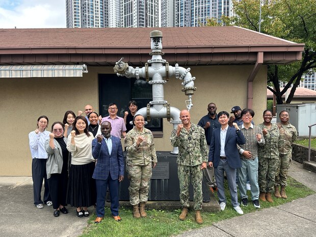 RDML George Bresnihan (center right) and Army Lt. Col. Jeremia Van (center left) gather around “Pipeman Pete” with staff at DLA Energy Indo-Pacific Korea headquarters. The statue, constructed with readily-available pipeline material, symbolizes esprit de corps among the petroleum workforce.