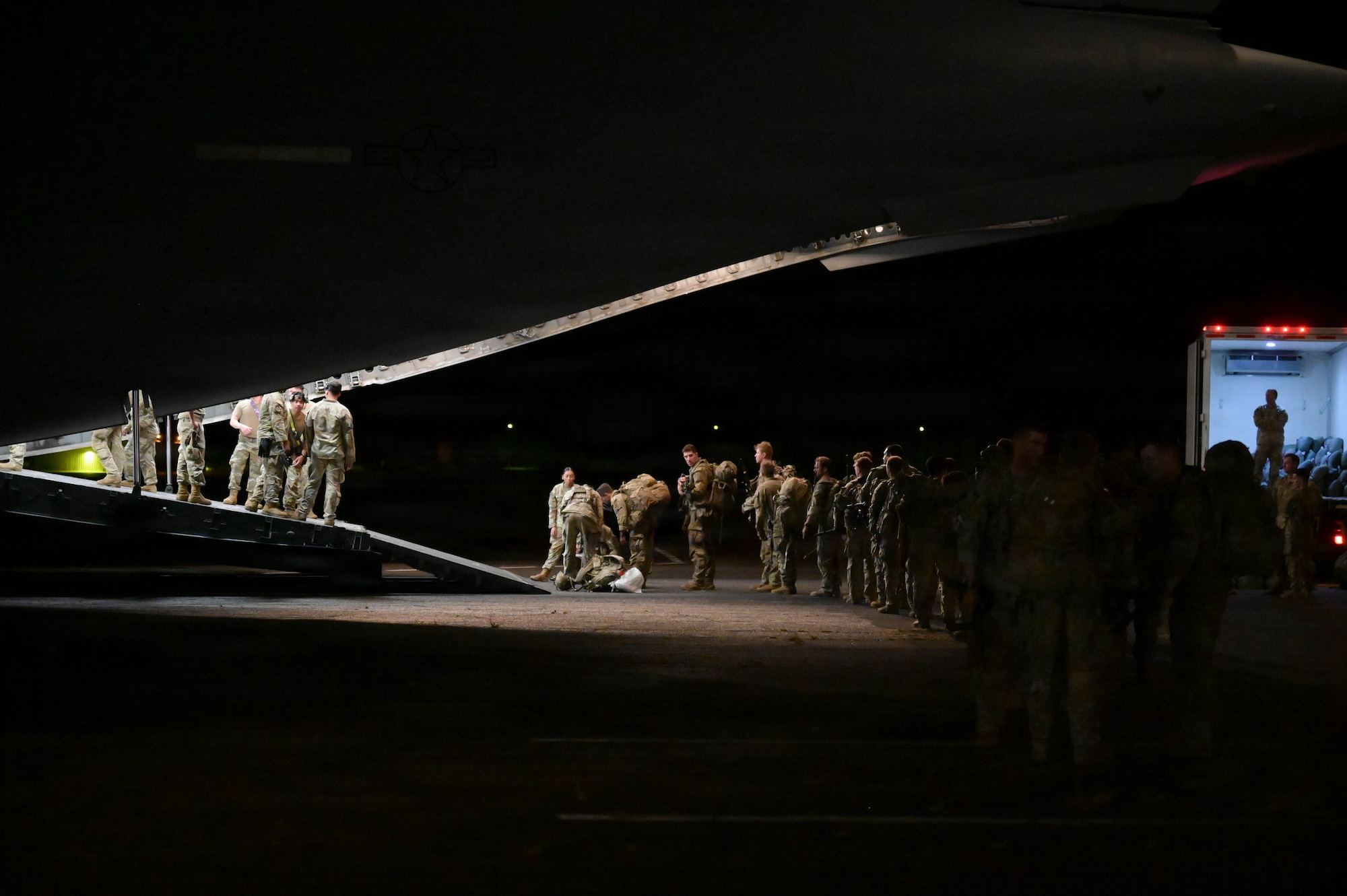Soldiers entering a U.S. Air Force aircraft at night.
