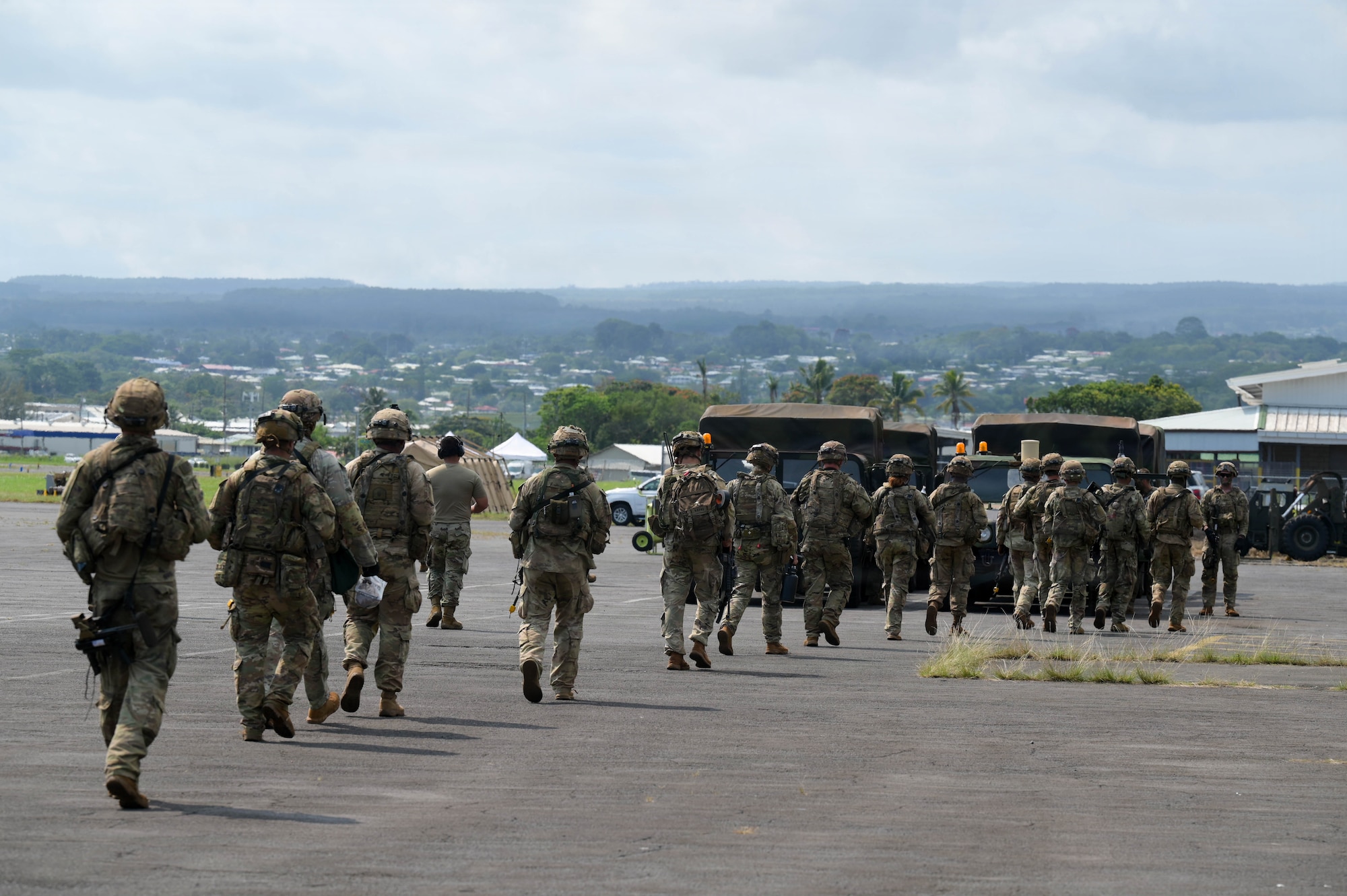 U.S. Army soldiers walk towards shelter on a flightline.