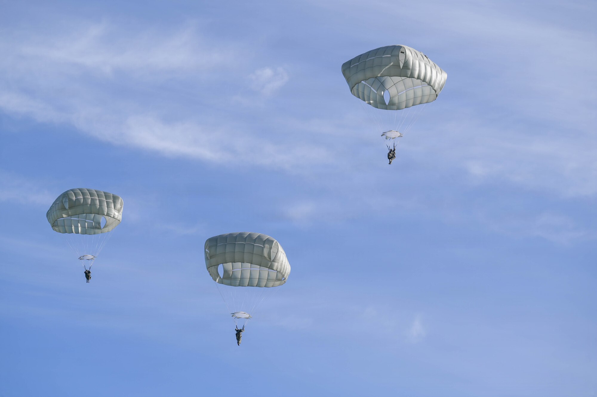 Parachuted soldiers floating towards the ground.