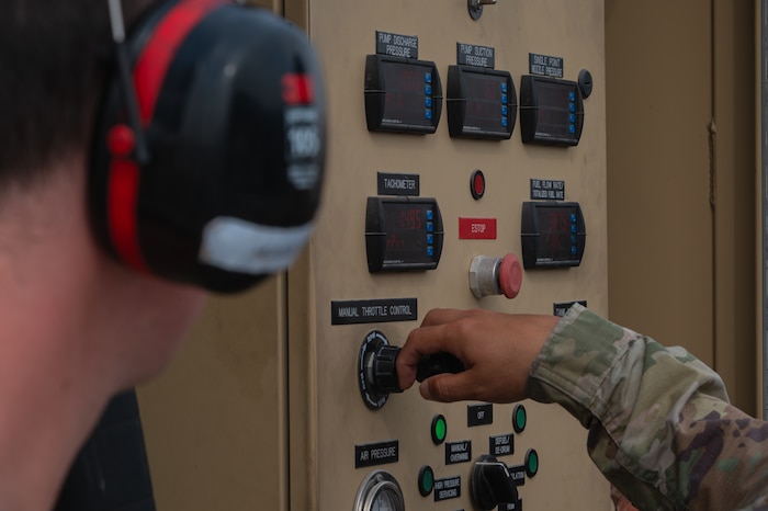 An Airman turns a knob on a refueling truck control panel
