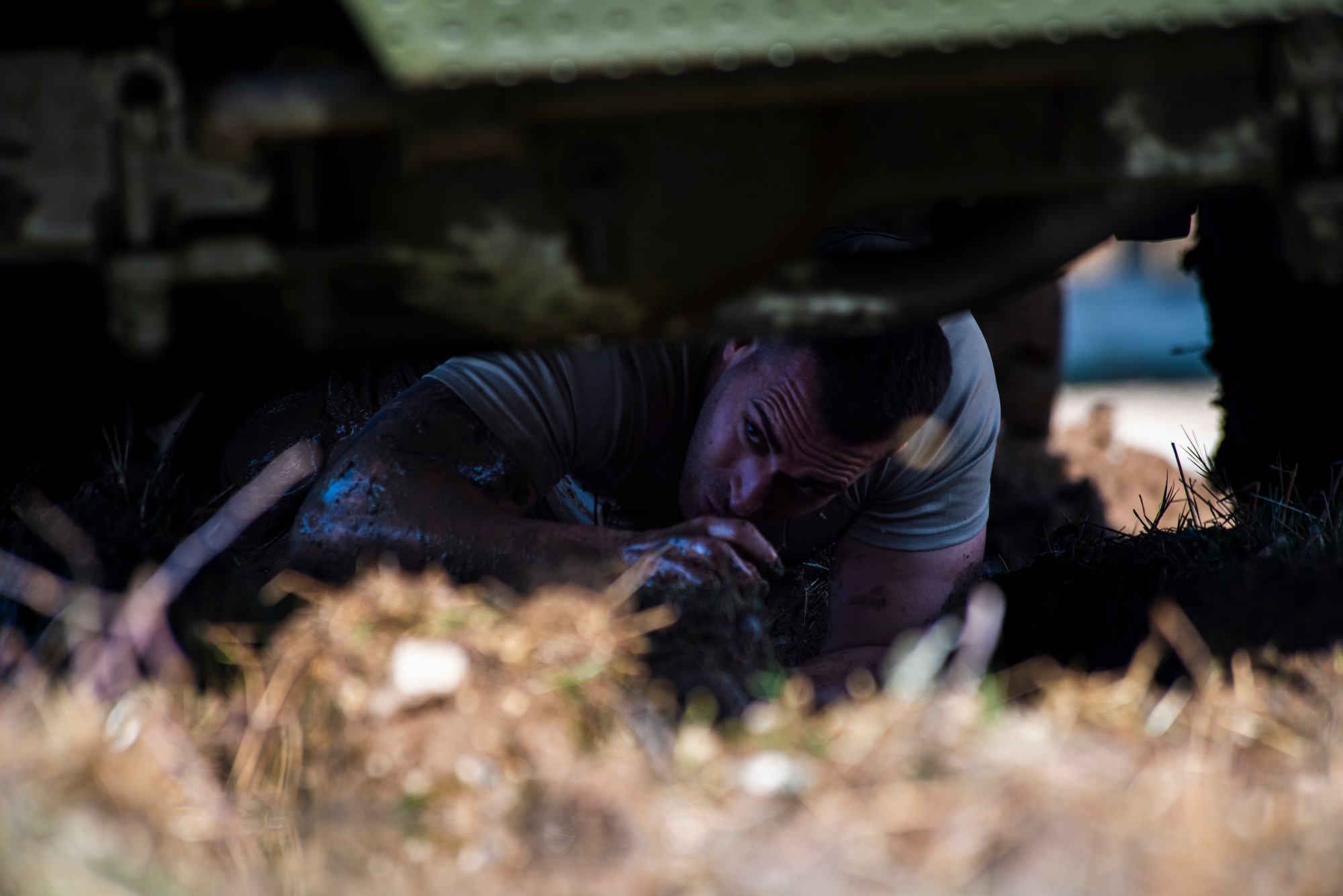 A Spanish service member crawls beneath a vehicle during an endurance challenge