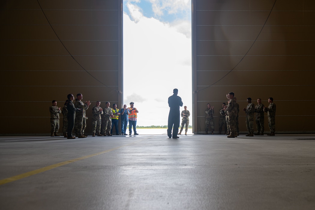 People listen to a man speaking in front of a group of people.