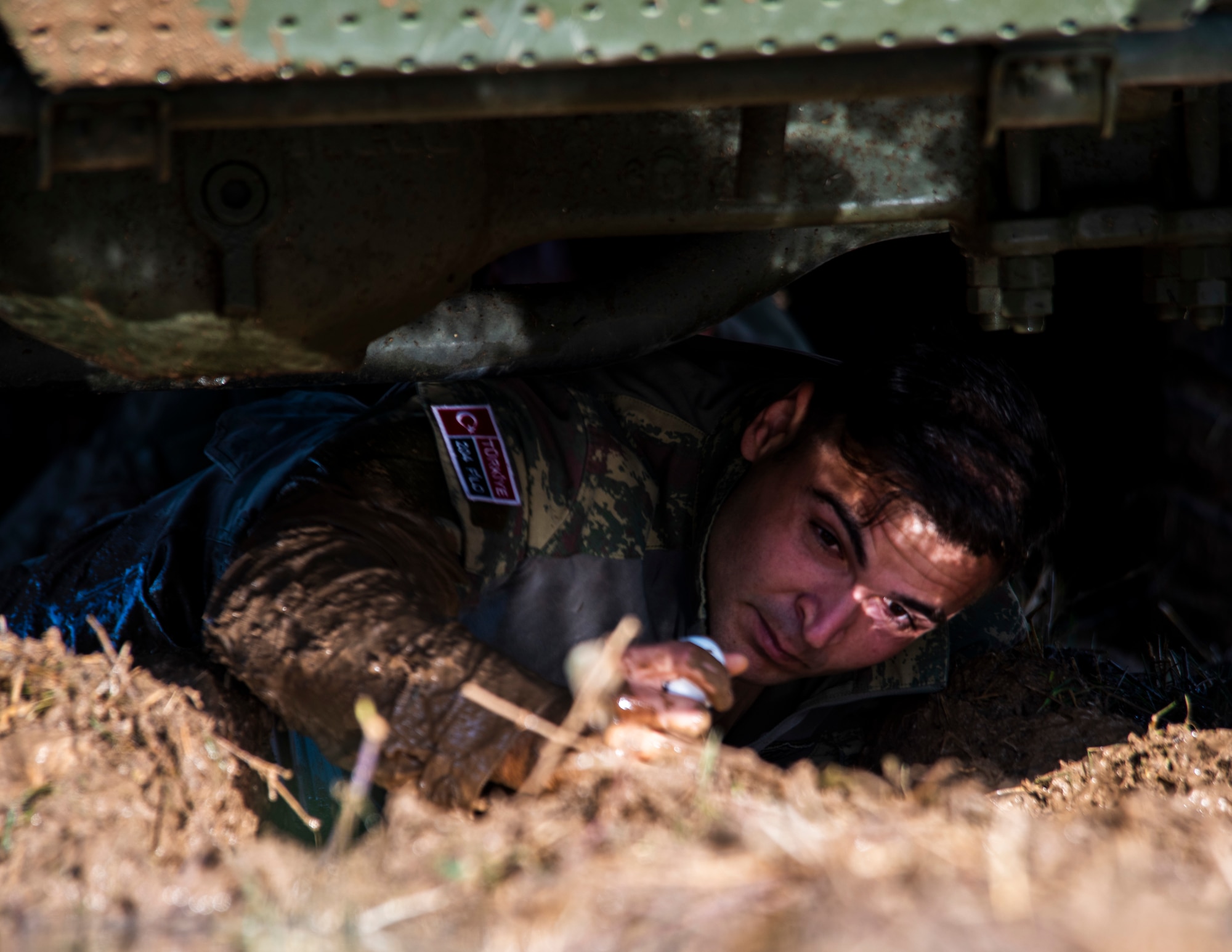 A Turkish Air Force service member crawls beneath a vehicle