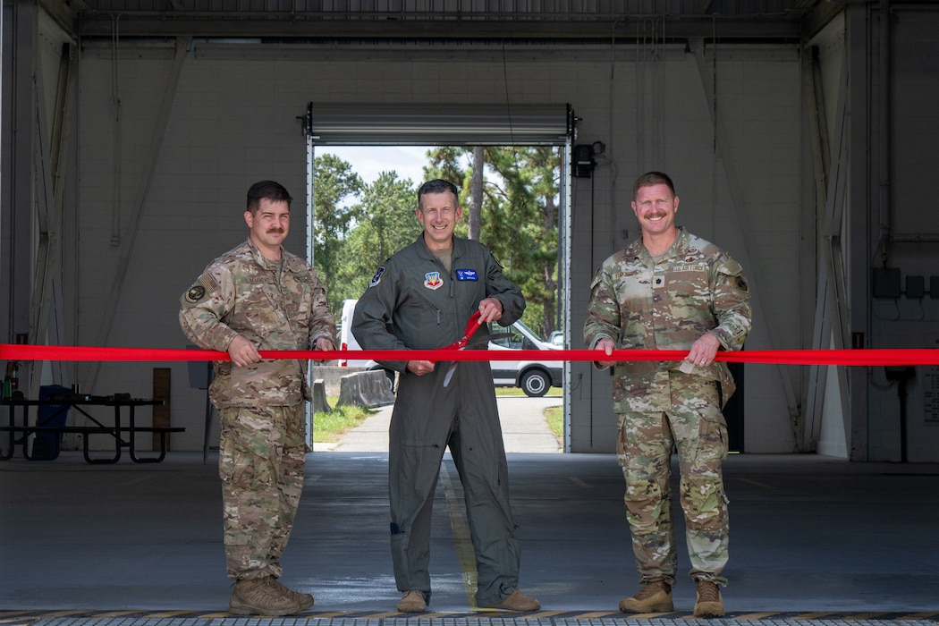 Men pose for a photo while cutting a ribbon.