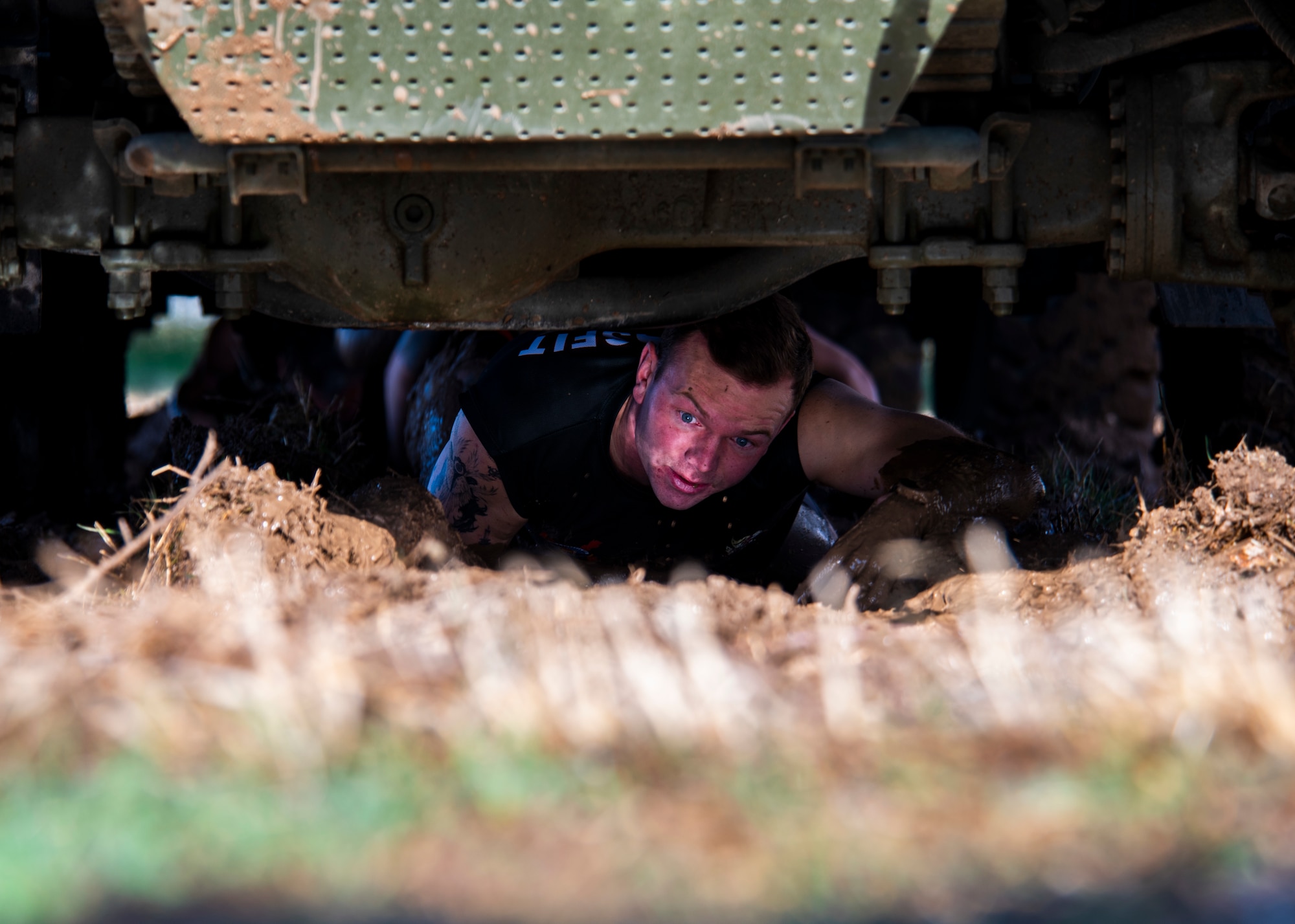U.S. service member crawls under a vehicle during endurance challenge