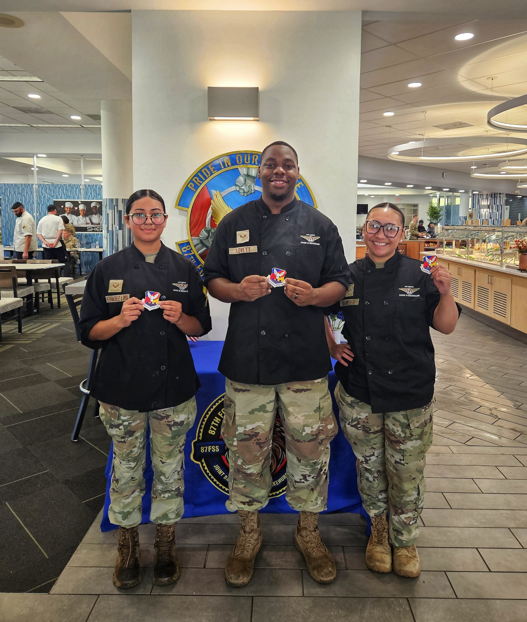 U.S. Air Force Senior Airman Nidia Hernandez-Lima (left), Senior Airman Jaylen Lovett (center) and Airman 1st Class Shanise Caampued, 87th Force Support Squadron chefs, show off their squadron patch after competing in the 87th FSS Salute Hospitality Epicurean Faceoff at Joint Base McGuire-Dix-Lakehurst, New Jersey in September. Caampued earned first place and will represent JBMDL at the national SHEF competition at the Culinary Institute of America in San Antonio, Texas. (Air Force Courtesy Photo)