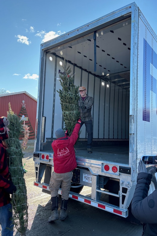 Three men unload trees from a delivery truck.