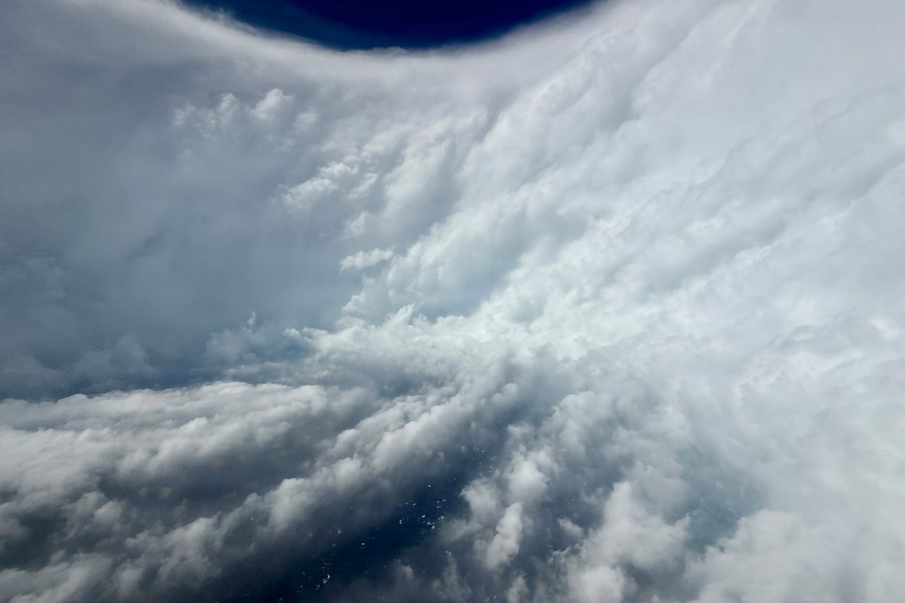 An aerial view of the inside of a hurricane from a military aircraft, with a wall of clouds going around in a circle.