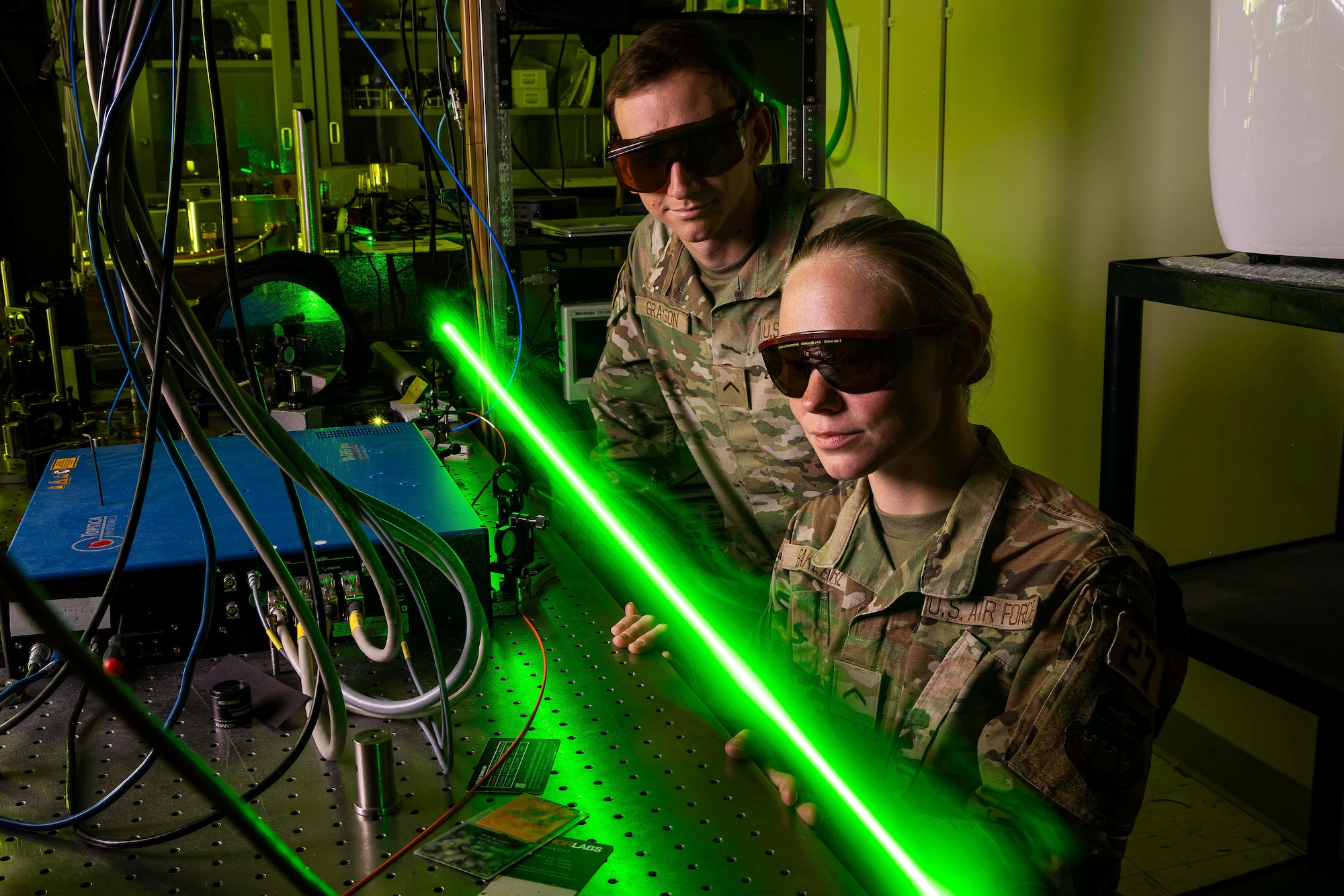 Photo of cadets in a research lab, with goggles on, staring at a green laser beam