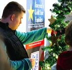 Alec Tobias, 16, a volunteer with Gold Star Mission, affixes an ornament honoring a fallen service member on the tree during the American Gold Star Families’ Fallen Heroes Tree of Honor Tree Lighting Ceremony.