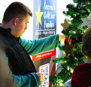 Alec Tobias, 16, a volunteer with Gold Star Mission, affixes an ornament honoring a fallen service member on the tree during the American Gold Star Families’ Fallen Heroes Tree of Honor Tree Lighting Ceremony.