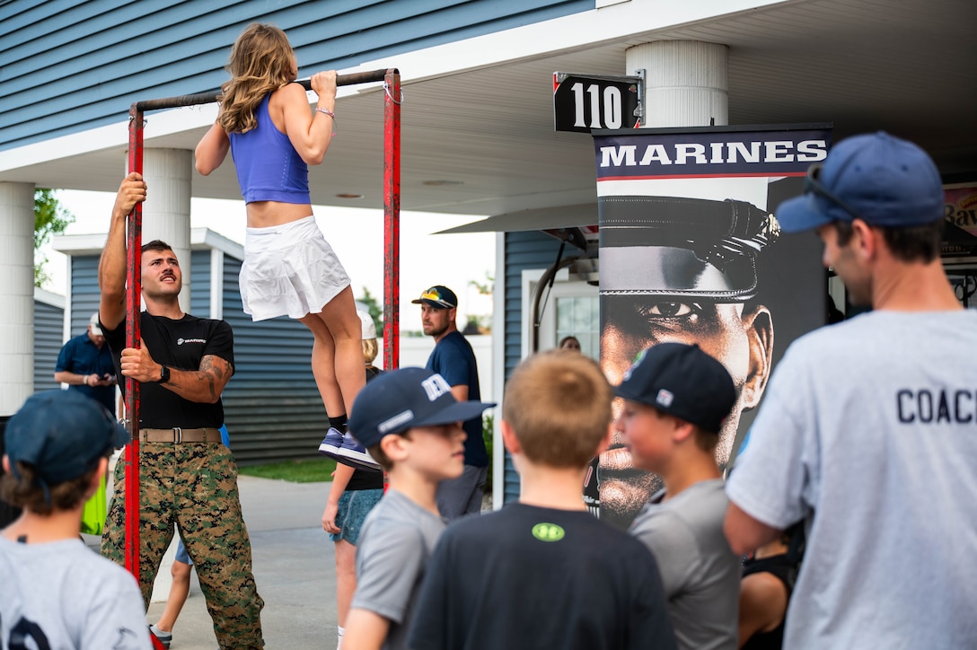 A local competes in a pull-up challenge hosted by U.S. Marine recruiters with Recruiting Station Lansing, 4th Marine Corps District, during a Pit Spitters baseball game at Turtle Creek Stadium, Traverse City, Michigan, July 1, 2025. The recruiters participated in this event to engage and educate the local community about Marine Corps opportunities and careers. (U.S. Marine Corps photo by Sgt. Israel Sheber)