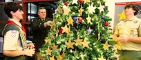 Brig. Gen. Lenny Williams affixes an ornament honoring a fallen service member on the tree with members of Bloomington Boy Scout Troop 19.