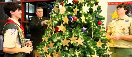 Brig. Gen. Lenny Williams affixes an ornament honoring a fallen service member on the tree with members of Bloomington Boy Scout Troop 19.