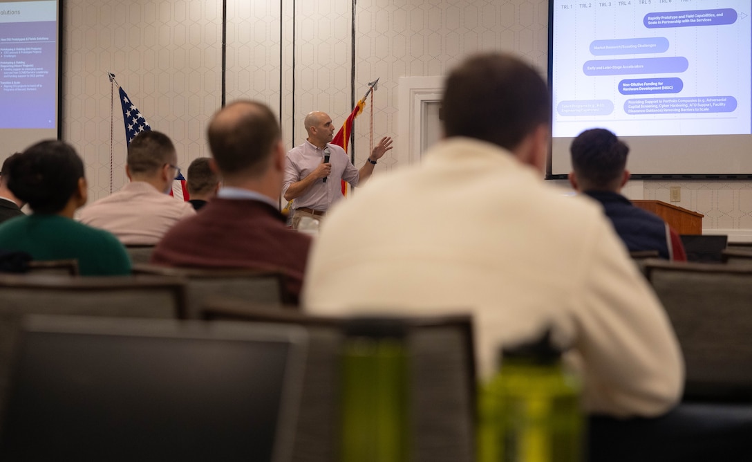 U.S. Marine Corps Lt. Col. Nicholas E. Ksiazek, a member of the Marine Innovation Unit currently assigned as an embedded officer at the Defense Innovation Unit, delivers a presentation on the initiatives currently underway at DIU during an all-hands training in White Plains, New York, Nov. 20, 2025. Ksiazek provided Marines with a broad understanding of the collaboration taking place between MIU and DIU to help advanced defense innovation efforts. Established in 2022, the Marine Innovation Unit leverages the talent of the Marine Corps Reserve to accelerate the adoption of advanced capabilities, transform Naval Service capacity for technology employment, and retain and invest in Total Force human capital. (U.S. Marine Corps photo by Cpl. Kanoa Thomas)