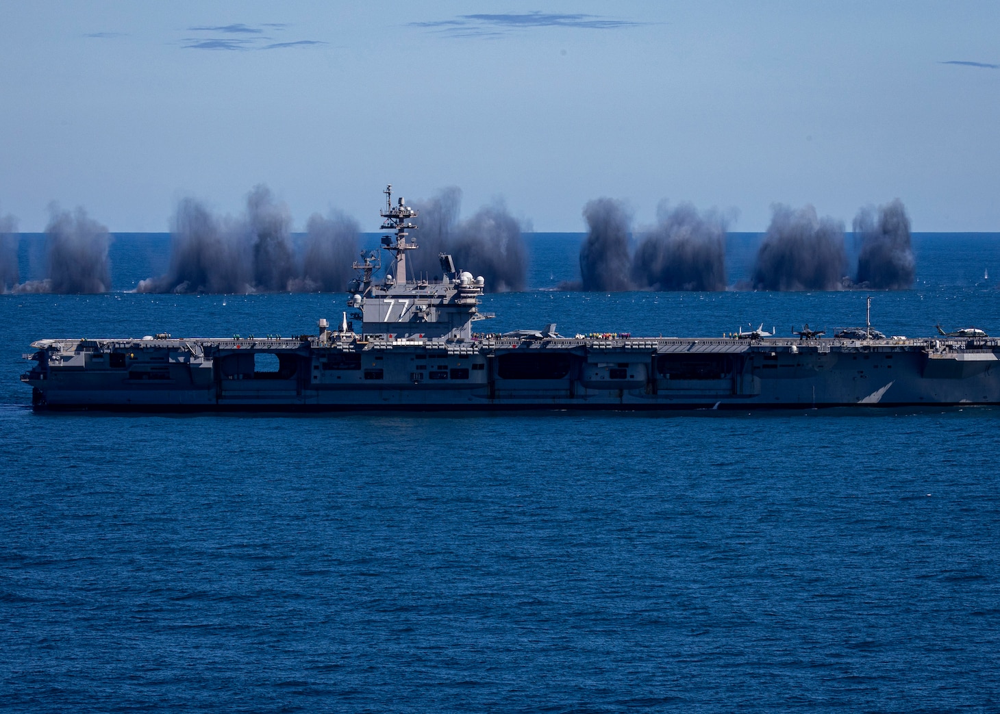 he Nimitz-class aircraft carrier USS George H.W. Bush (CVN 77) transits the Atlantic Ocean while four F/A-18E Super Hornets, attached to the “Pukin Dogs” of Strike Fighter Squadron (VFA) 143 drop bombs for a “Wall of Water” showcase in support of the Titans of the Sea Presidential Review. The Titans of the Sea Presidential Review is one of many events taking place throughout the country to showcase maritime capabilities as part of the U.S Navy’s 250th birthday. America is a maritime nation. For 250 years, America’s Warfighting Navy has sailed the globe in defense of freedom.