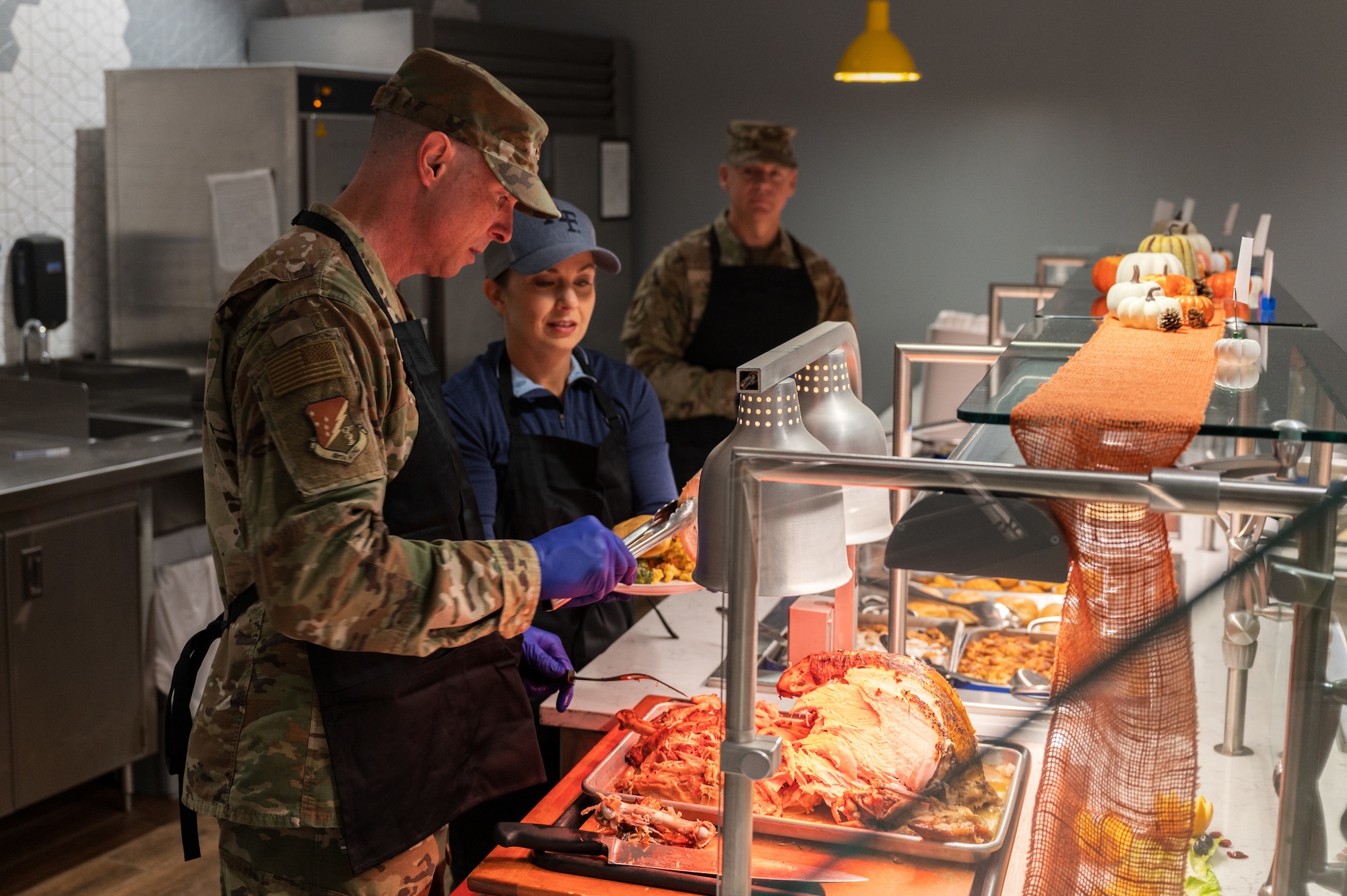U.S. Air Force Col. John Ethridge, 49th Wing commander, left, and Tricia Ethridge, Holloman Spouses Organization member, prepare a Thanksgiving meal plate at the Shifting Sands Dining Facility at Holloman Air Force Base, Nov. 27, 2025.
