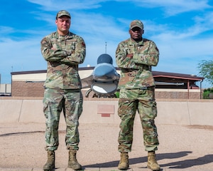 U.S. Air Force Senior Airman Ryan Namasaka, 56th Medical Support Squadron medical laboratory technician (right) and Senior Airman Calston Harris, 56th Equipment Maintenance Squadron armament maintenance technician (left), pose for a photo outside of the 56th Fighter Wing Headquarters, Nov. 4, 2025, at Luke Air Force Base, Arizona.