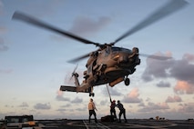 U.S. Sailors attach a cargo hook to an MH-60R Sea Hawk, assigned to the “Battle Cats” of Helicopter Maritime Strike Squadron (HSM) 73, on the flight deck of the Arleigh Burke-class guided-missile destroyer USS Wayne E. Meyer (DDG 108) in the Philippine Sea, Nov. 26, 2025.