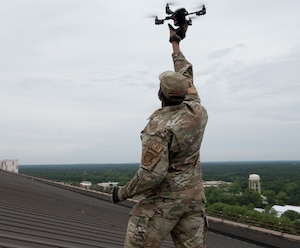 U.S. Air Force Staff Sgt. Jermaine Brown, 621st Contingency Response Group standards evaluator, observes a drone being used to inspect Hangar 1 on Joint Base McGuire-Dix-Lakehurst, New Jersey on June 21, 2022. The 621st Contingency Response Squadron partnered with the 787th Civil Engineering Squadron to assist them in surveilling facilities for damage.