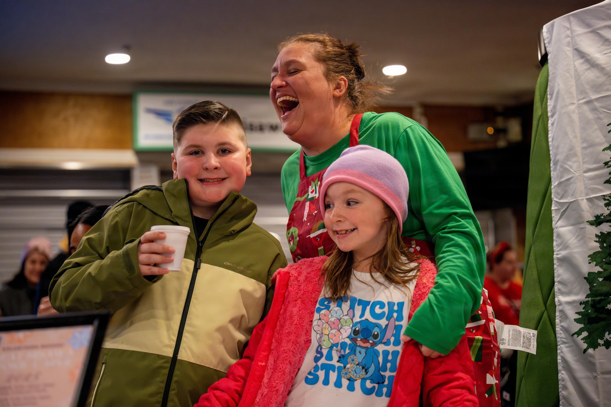 A family laughs while posing for a photo during a tree lighting ceremony.