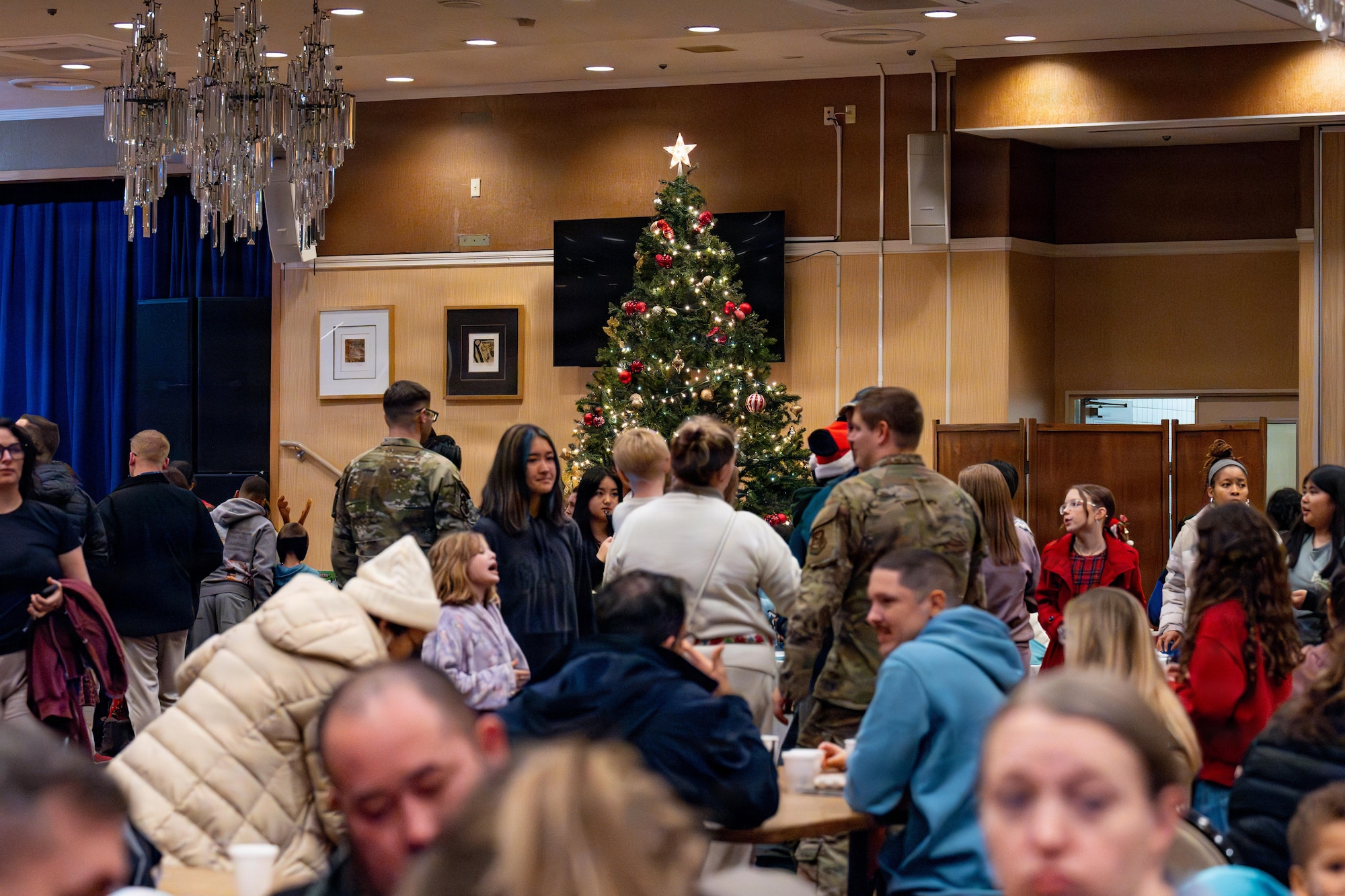 A Christmas tree shines over a crowd after a tree lighting ceremony.