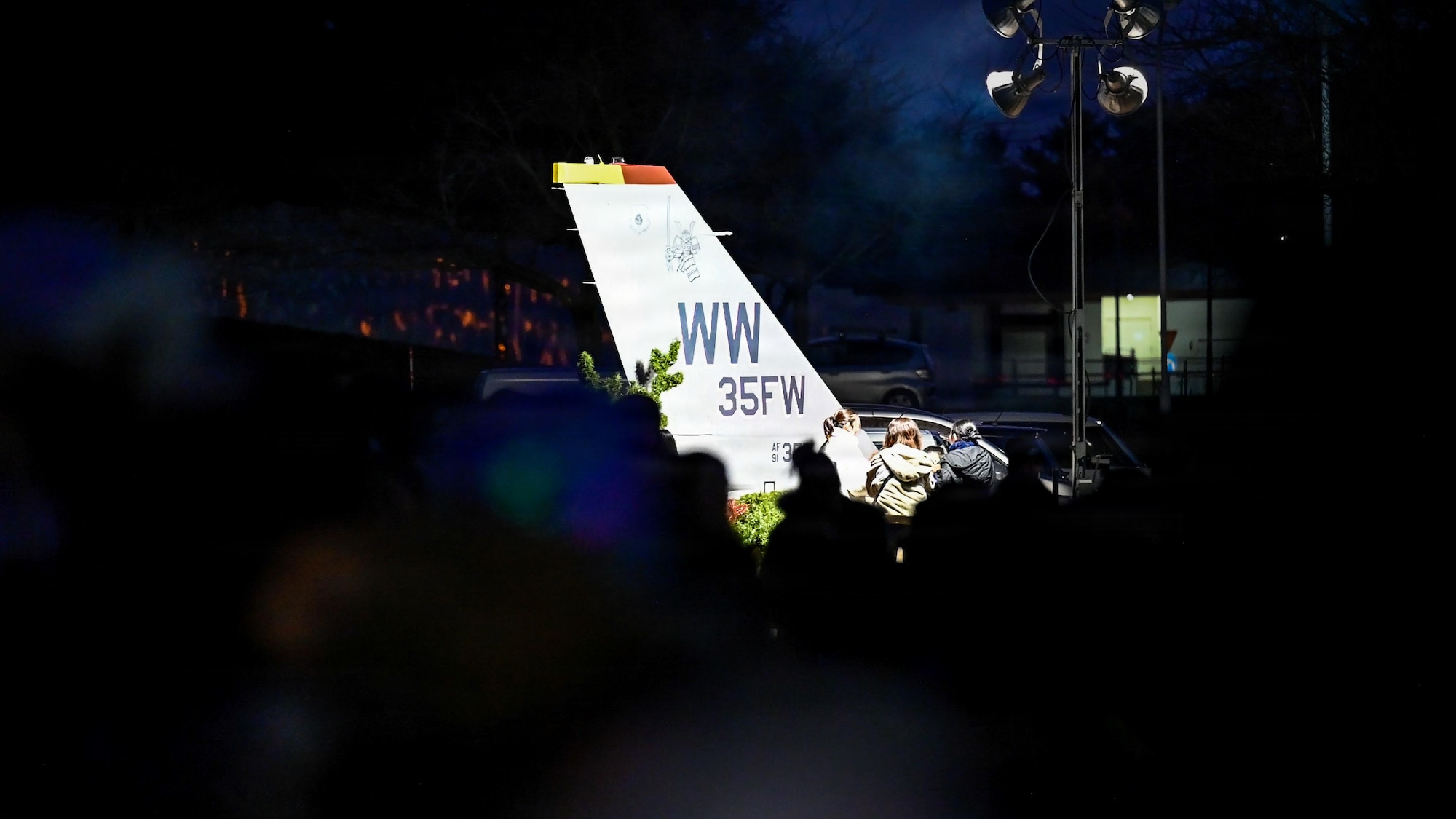 The 35th Fighter Wing (FW) U.S. Air Force F-16 Fighting Falcon tail static display is illuminated during a tree lighting ceremony.