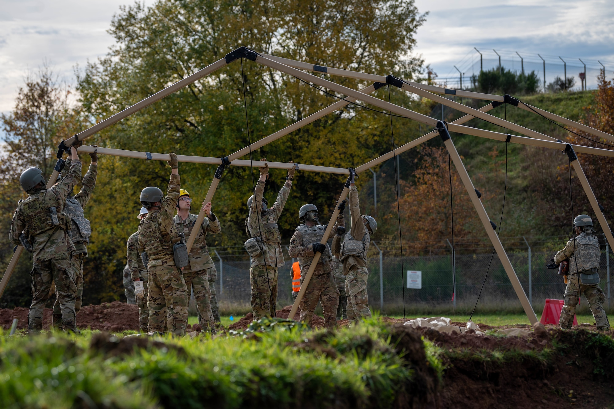 U.S. Air Force Airmen assigned to the 52nd Fighter Wing construct a tent during the first Airman Leadership School field training exercise at Spangdahlem Air Base, Germany, Nov. 6, 2025. The ALS field training exercise challenged students to operate in a simulated deployed environment. (U.S. Air Force photo by Airman 1st Class Sydney Franklin)