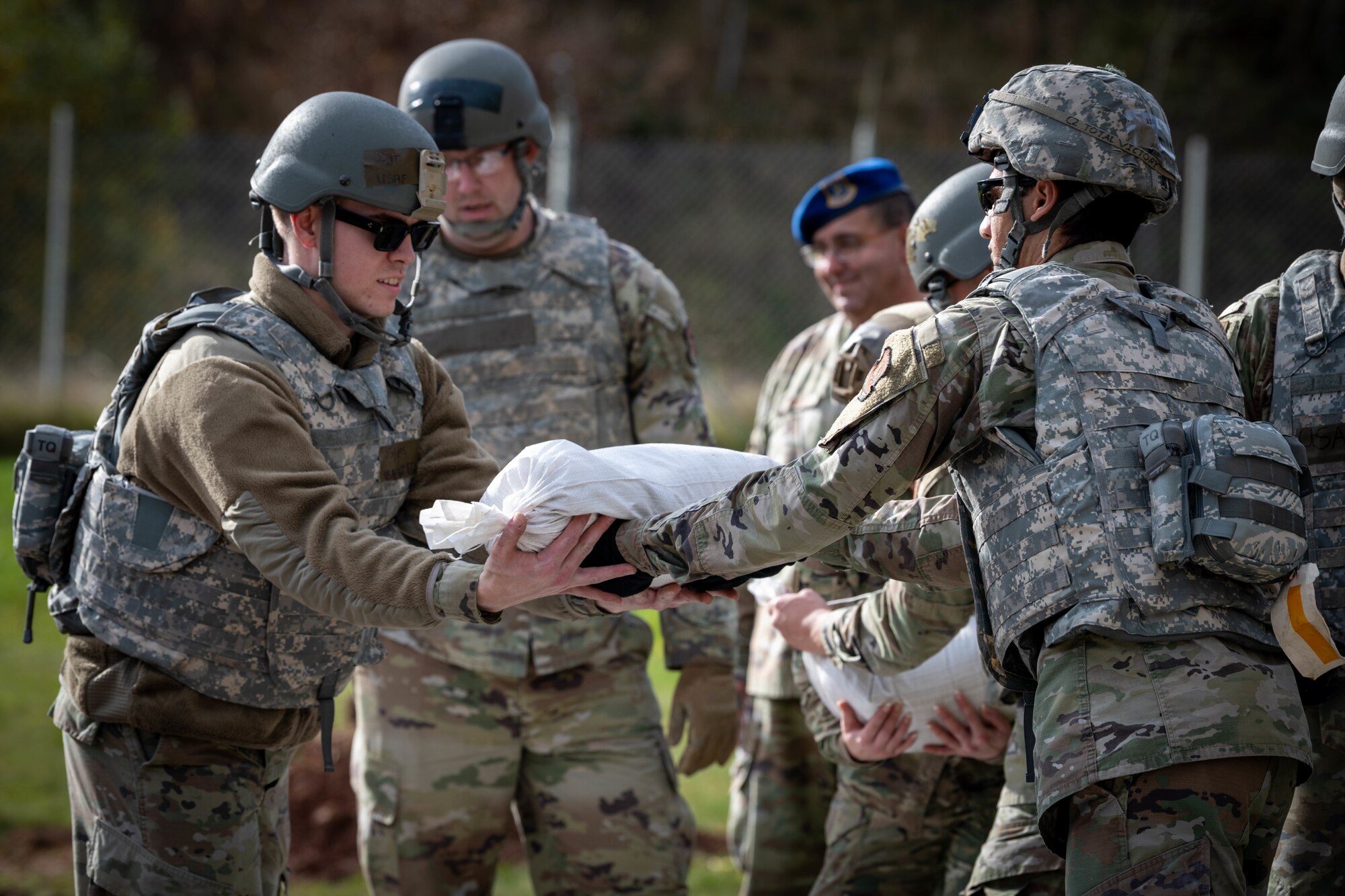 U.S. Air Force Airmen assigned to the 52nd Fighter Wing pass each other sandbags to build a barrier during the first Airman Leadership School field training exercise at Spangdahlem Air Base, Germany, Nov. 6, 2025. The teamwork focused scenario was designed to develop leadership, communication and problem-solving skills in a simulated deployed environment. (U.S. Air Force photo by Airman 1st Class Sydney Franklin)