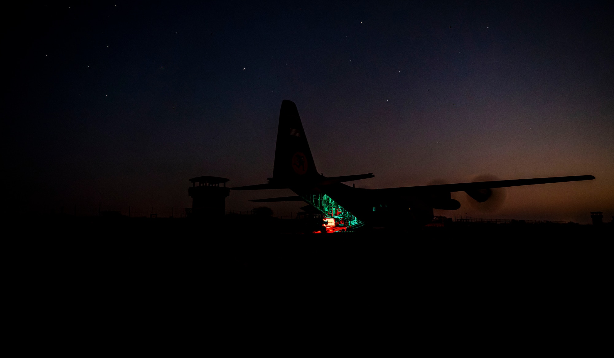 Airmen assigned to the 75th Expeditionary Airlift Squadron offload cargo from a C-130H Hercules cargo aircraft at night