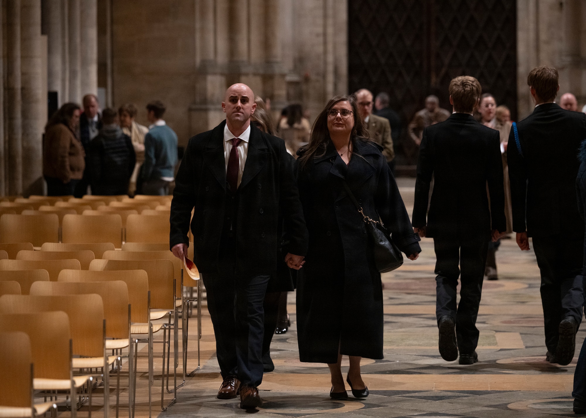 U.S. Air Force Chief Master Sgt. James Wall, 100th Air Refueling Wing command chief, and his wife, Christina Wall, walk down an aisle to find their seating at Ely Cathedral, Nov. 26, 2025. British and American nationals attended a Thanksgiving service held for U.S. service members stationed in the U.K. (U.S. Air Force photo by Staff Sgt. Nash Truitt)