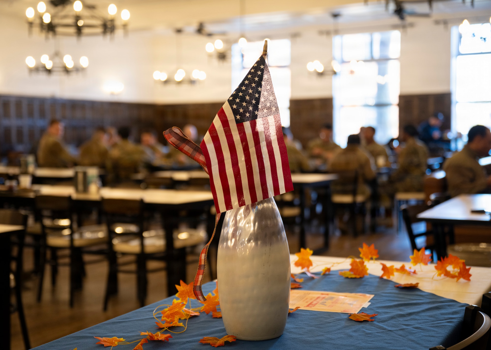 A U.S. flag rests in a vase on a table at the Gateway Dining Facility at RAF Mildenhall, Nov. 26, 2025. The 100th Force Support Squadron and base leadership prepared and served meals to Airmen who are stationed away from home this holiday season. (U.S. Air Force photo by Staff Sgt. Nash Truitt)