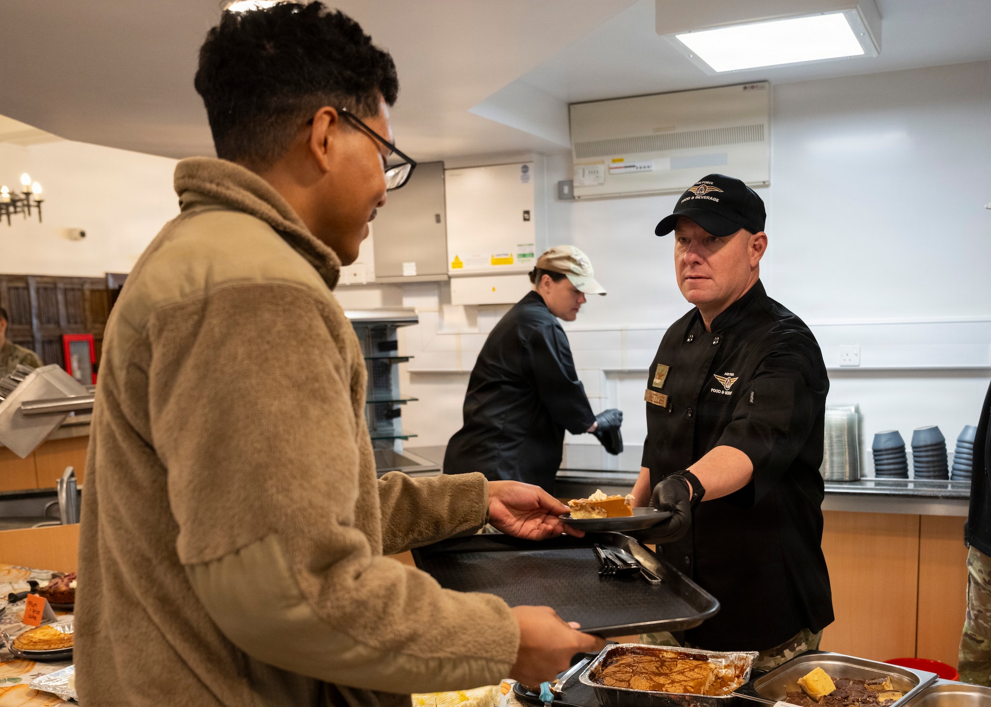 Col. Scott Metzler, 100th Mission Support Group commander, serves food to Airmen at RAF Mildenhall, Nov. 26, 2025. The 100th Force Support Squadron and base leadership prepared and served meals to Airmen who are stationed away from home this holiday season. (U.S. Air Force photo by Staff Sgt. Nash Truitt)