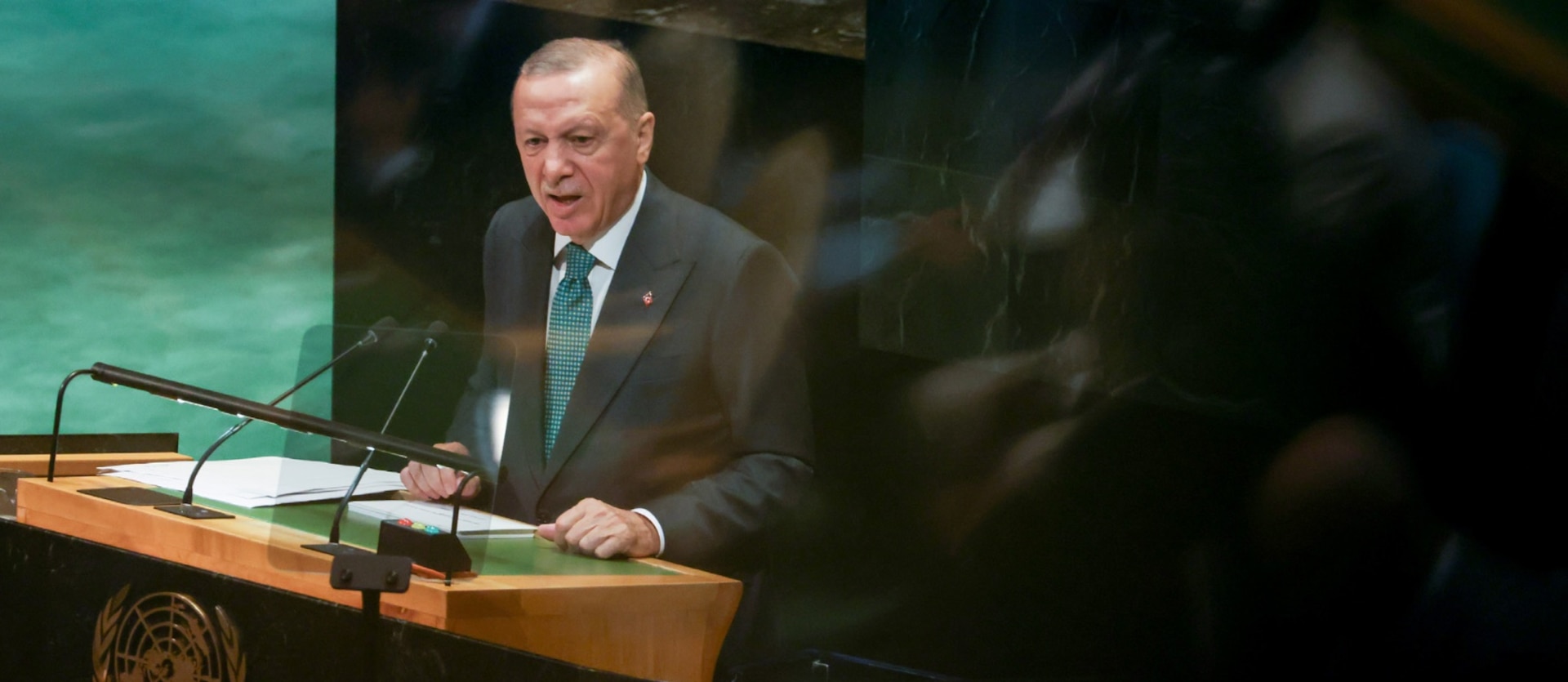 Turkish President Recep Tayyip Erdogan stands behind a podium wearing a suit, and delivers a fiery speech at the United Nations General Assembly in New York.