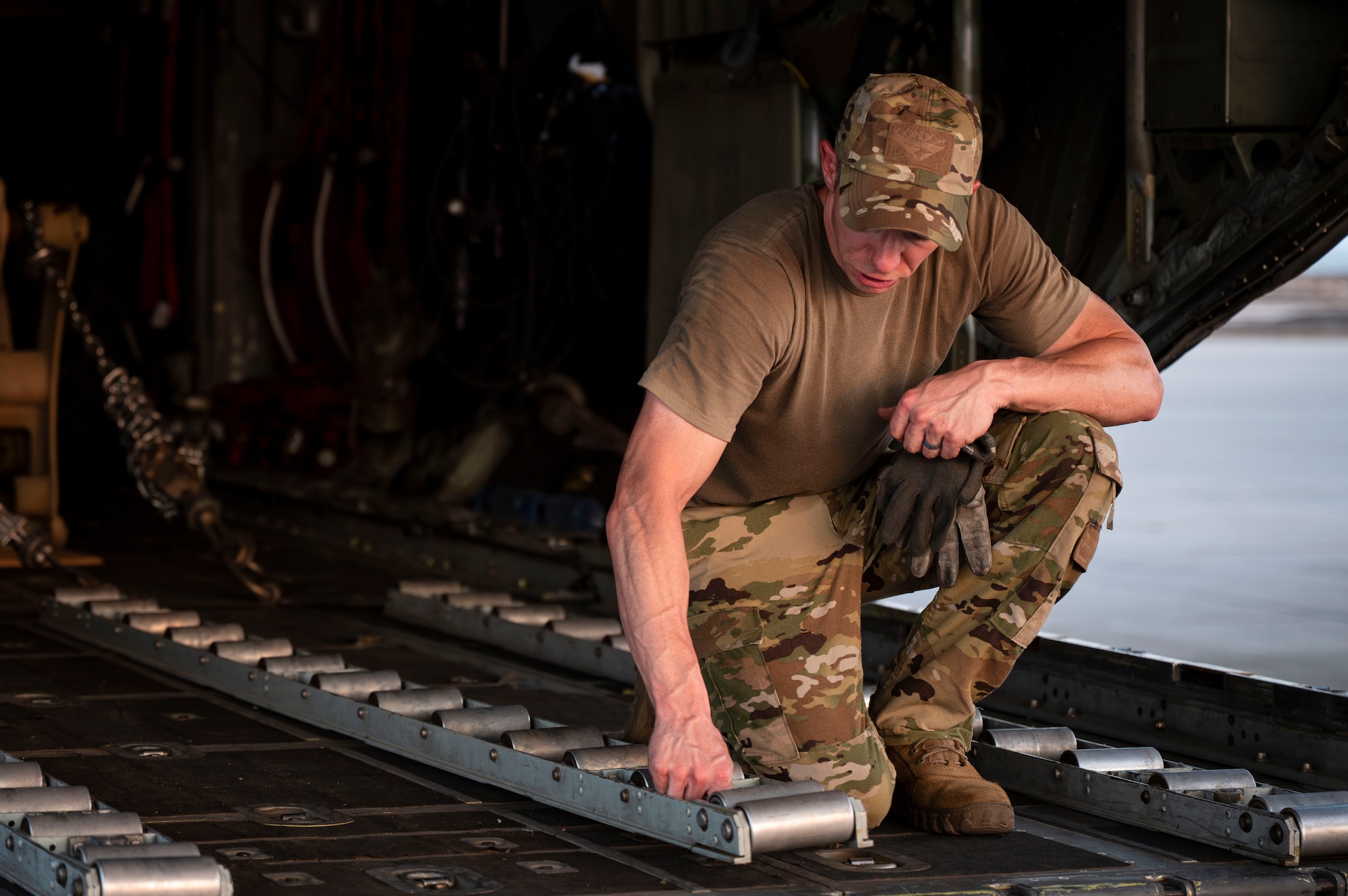 Master Sgt. Leon Bardwell, 75th Expeditionary Airlift Squadron loadmaster, positions a roller track for cargo to assist with onloading cargo